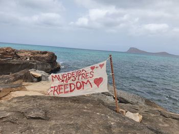 Text on rock at beach against sky