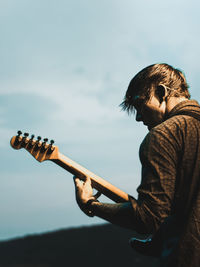 Man playing guitar against sky