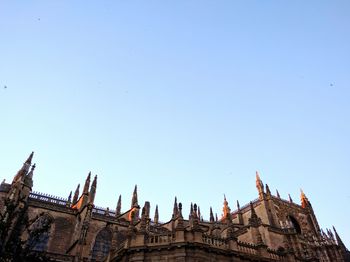 Low angle view of seville cathedral against clear sky in city