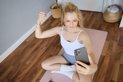 Portrait of young woman sitting on hardwood floor