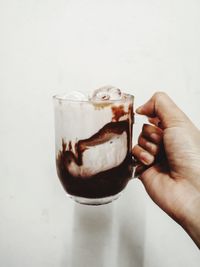 Hand holding ice cream cone against white background