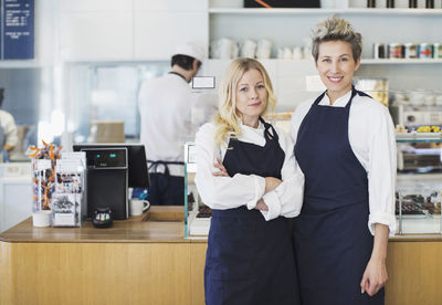 Portrait of confident female workers standing in cafe
