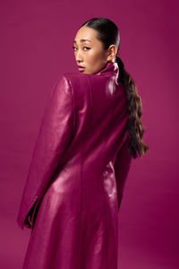 Portrait of young woman standing against yellow background