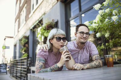 Young couple sitting in outdoor cafe drinking ice tea