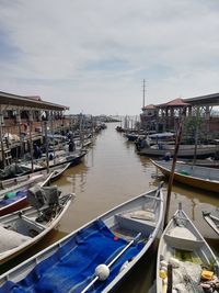 Boats moored in canal against sky