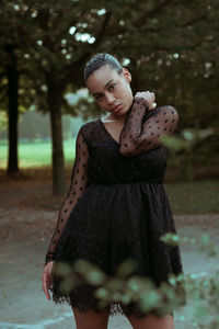 Portrait of woman with arms raised standing in park