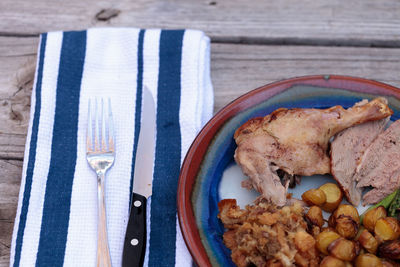 High angle view of roasted duck in plate by napkin on wooden table