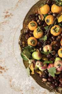 Autumn fruits dish. fresh raw apples, kaki and chestnuts on a golden tray