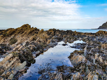 Rock formations by sea against sky