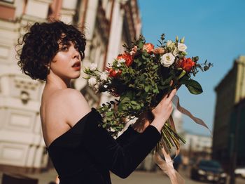 Side view of woman standing against pink flower