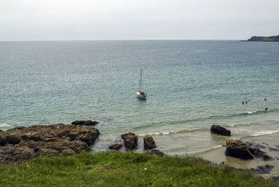 Sailboats moored on sea against sky