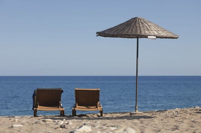 Deck chairs on beach against clear sky