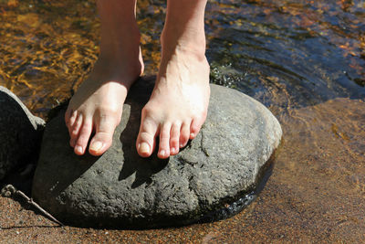 Low section of person on rock by lake