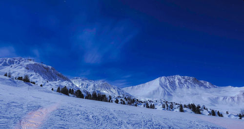 Scenic view of snowcapped mountains against blue sky