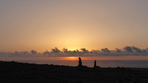 Silhouette people on beach against sky during sunset
