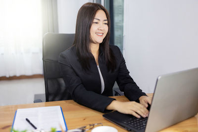 Young woman using phone while sitting on table