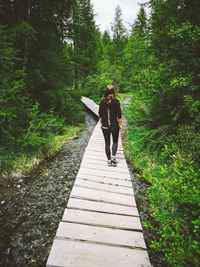 Full length of woman walking on footpath in forest