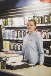 Portrait of smiling mature saleswoman standing in electronics store