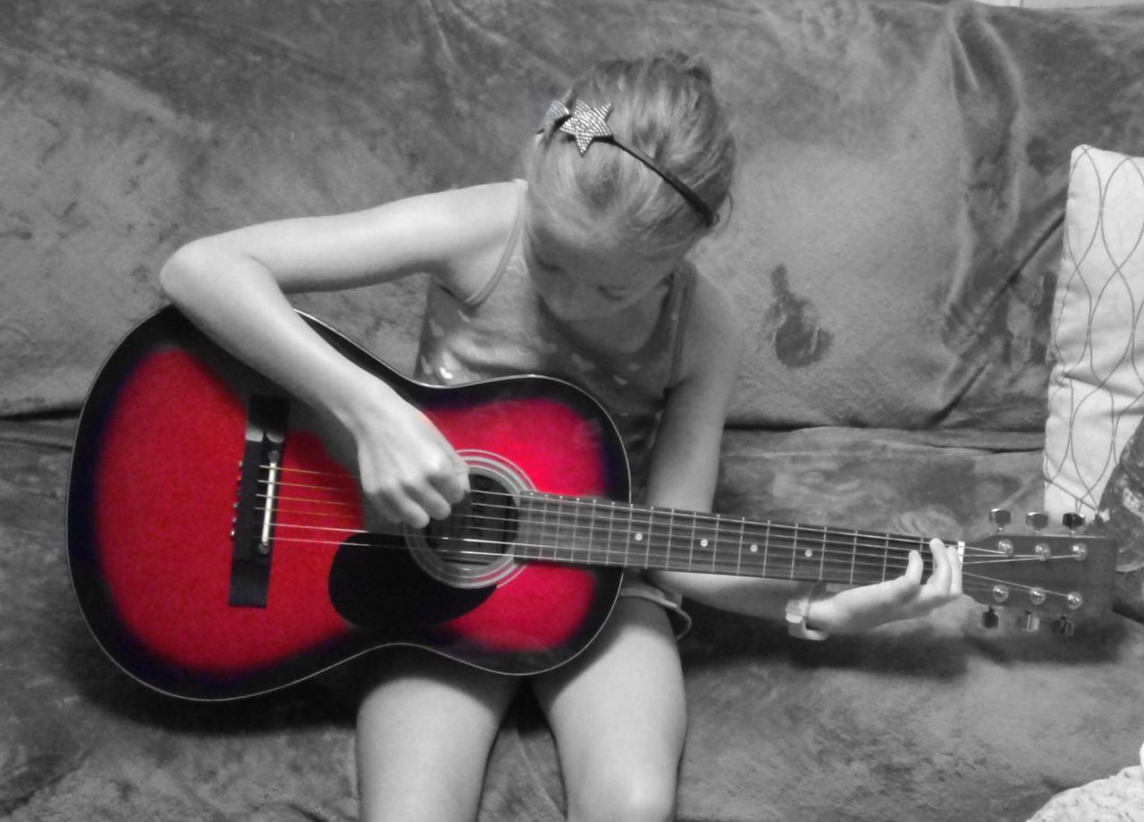 MIDSECTION OF WOMAN PLAYING GUITAR ON CARPET