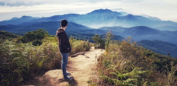 Rear view of woman looking at mountains against sky