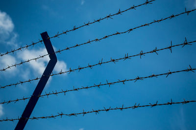 Low angle view of barbed wires against blue sky