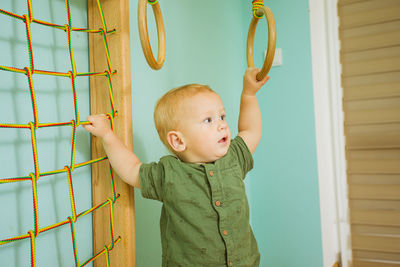 Cute boy looking away while standing against wall