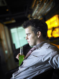 Side view of young businessman with drink at bar