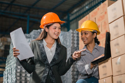 Portrait of businessman holding hardhat while standing in city