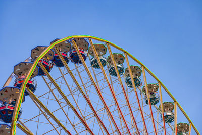 Low angle view of ferris wheel against clear blue sky