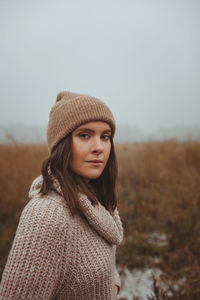 Portrait of woman standing in park against sky during winter