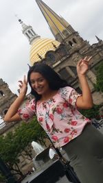 Portrait of smiling young woman against built structure