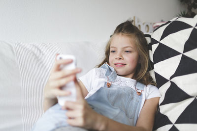 Portrait of smiling girl holding smart phone at home