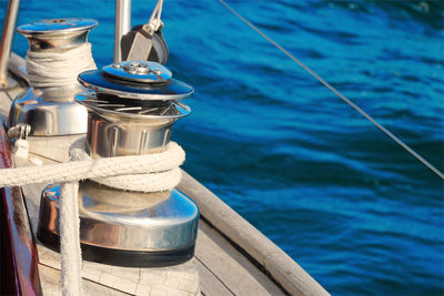 Close-up of rope tied to bollard against blue sea