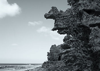 Rock formation on beach against sky