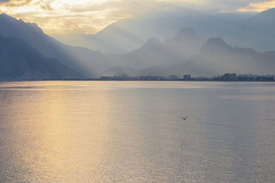 Scenic view of lake and mountains against sky during sunset