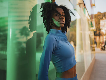 Woman wearing sports clothing leaning on glass wall