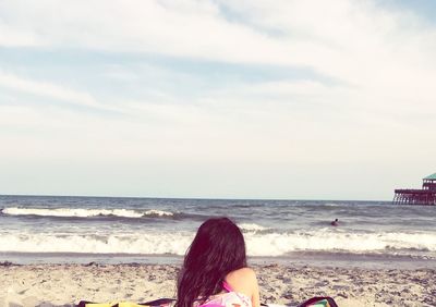 Rear view of woman at beach against sky