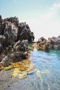 Rock formations in sea against sky