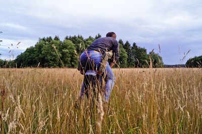 Rear view of woman giving piggyback to friend on agricultural field