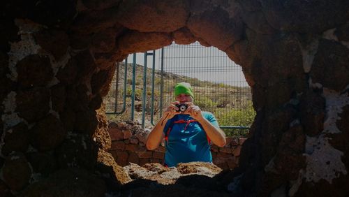 Man photographing seen through hole