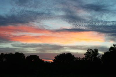 Low angle view of silhouette trees against dramatic sky