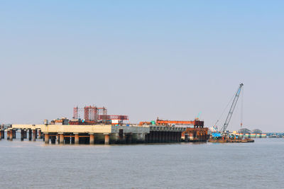 Commercial dock by sea against clear sky