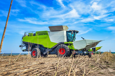 Agricultural harvester collects harvest in field. autumn field with harvester on sky background