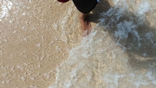 Low section of woman standing on sand