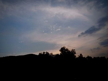 Silhouette of trees against cloudy sky