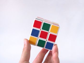 Close-up of hand holding toy against white background