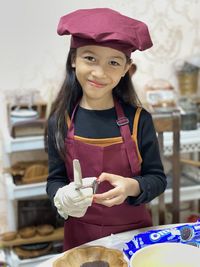 Portrait of a smiling girl holding knife nd cookies