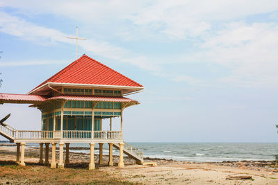 Built structure on beach by sea against sky