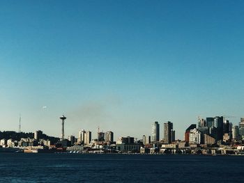 Sea and buildings against clear blue sky