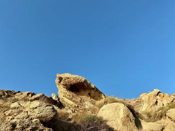 Low angle view of rock formation and clear blue sky